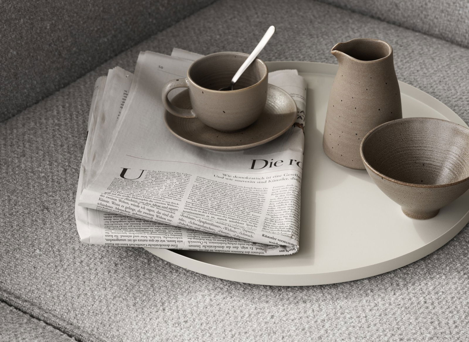 Cozy coffee setup with a newspaper, cup, and pottery on a stylish tray.