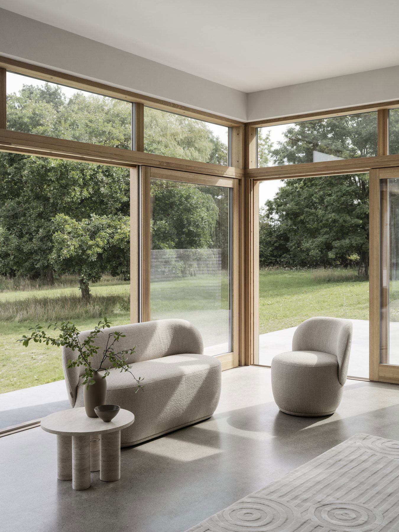 Modernes Wohnzimmer mit minimalistischer Möbeln und großen Fenstern, die einen Blick auf eine üppige grüne Landschaft bieten.