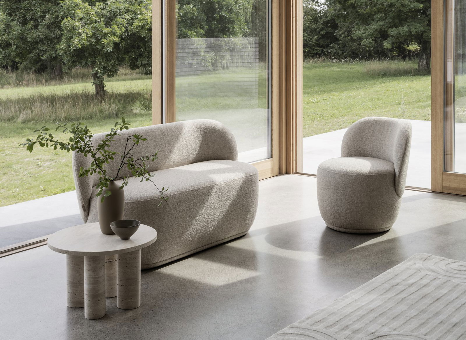 Moderner Wohnraum mit minimalistischem Sofa und Stuhl, akzentuiert durch natürliches Licht und Pflanzen.