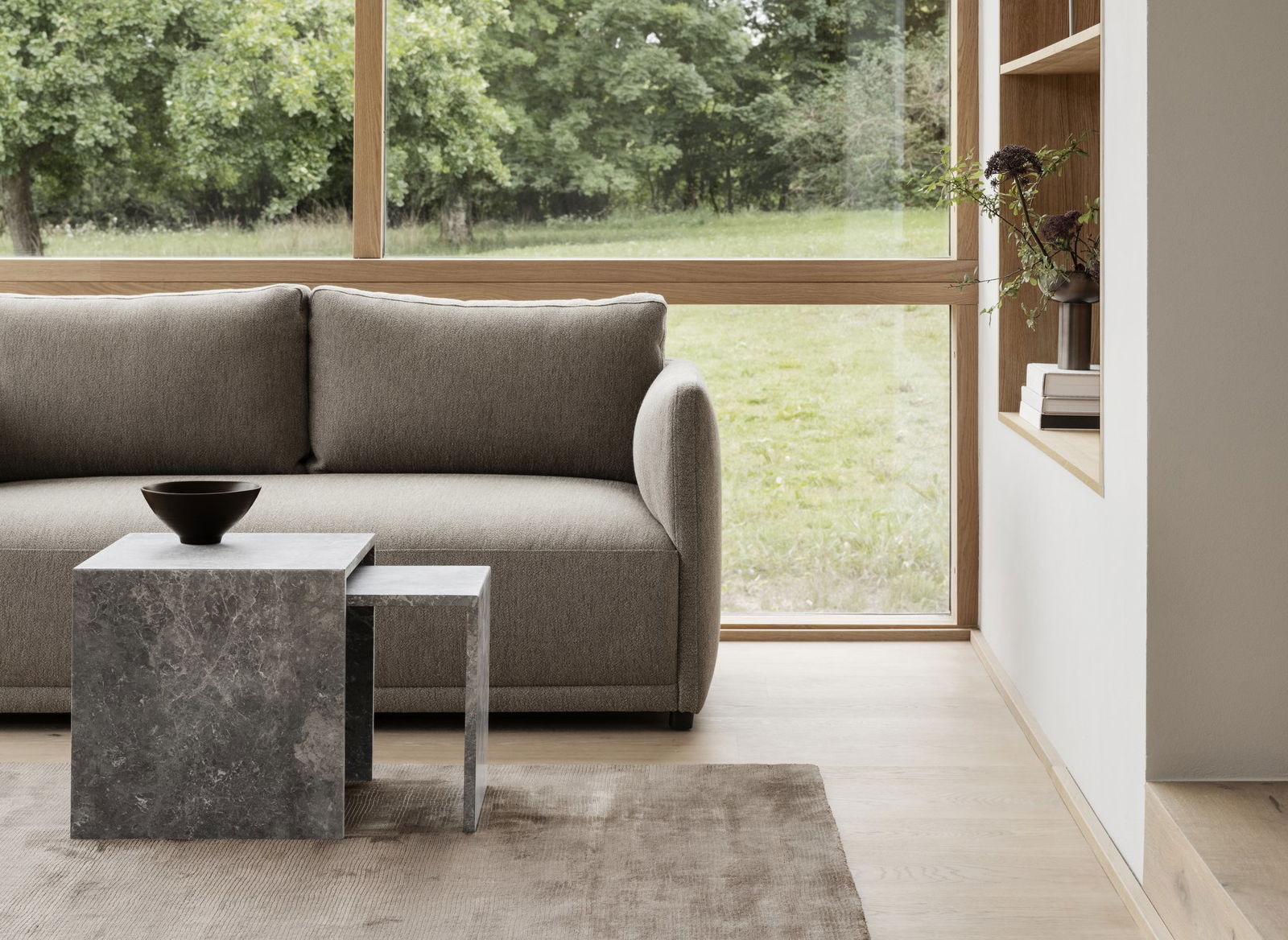 Modern living room featuring a gray sofa and minimalist coffee table by large windows.