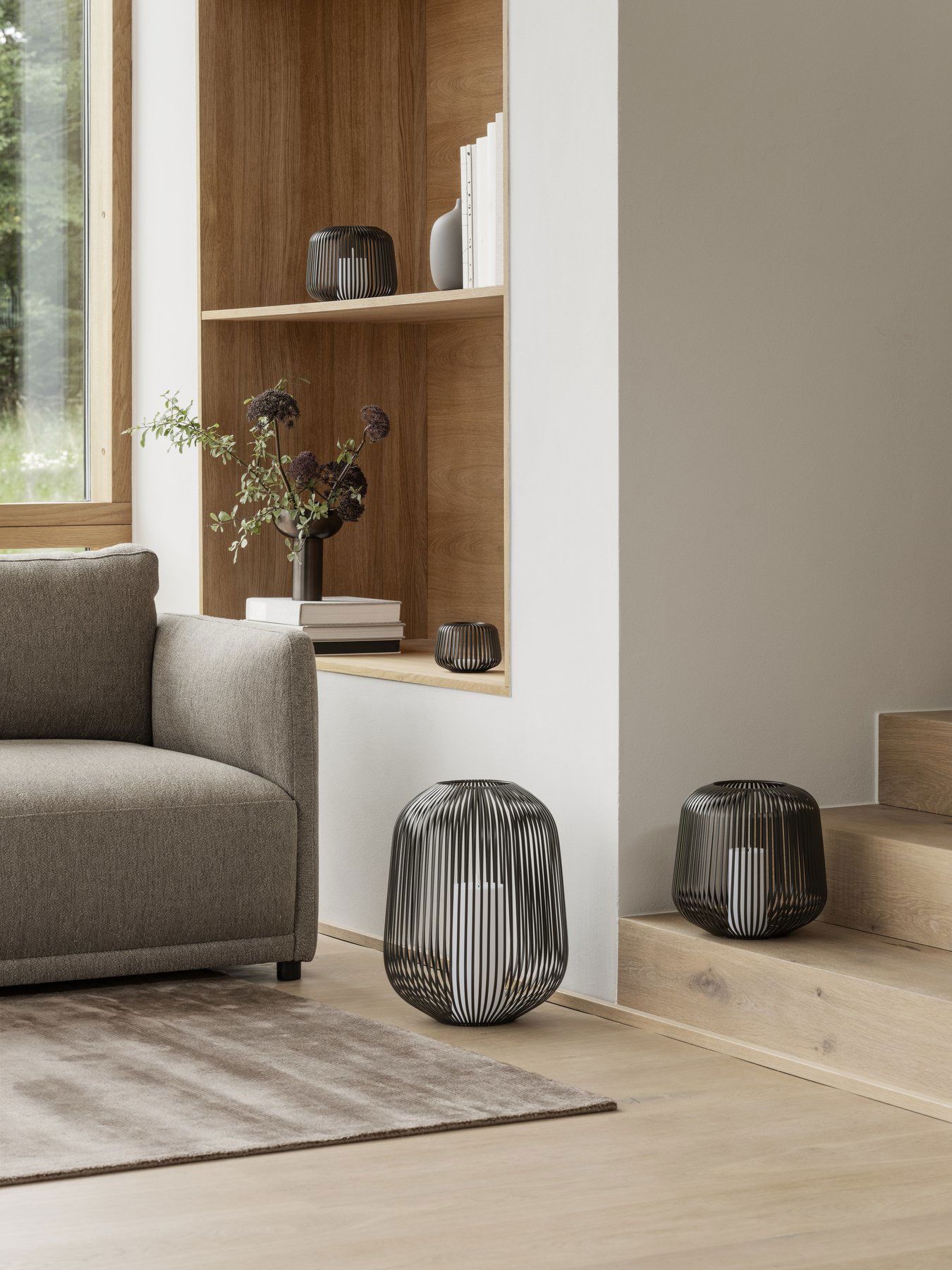 Modern living room with stylish wire lamps and neutral furnishings on wooden decor.