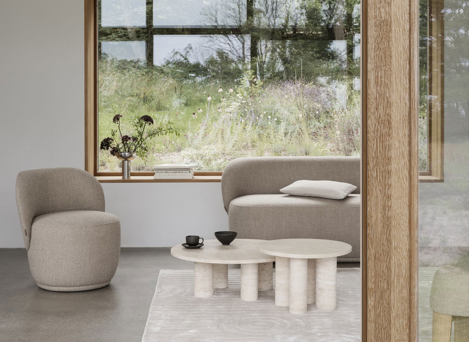 Moderner Wohnraum mit einem minimalistischen Sofa, einem runden Couchtisch und grünen Pflanzen draußen am Fenster.