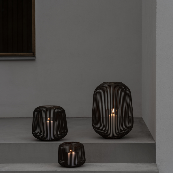 Stilvolle schwarze Drahtlaternen mit Kerzen auf modernen Betontreppen.