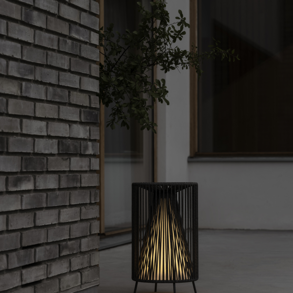 Stilvolle schwarze Lampe, die einen modernen Außenbereich neben einer strukturierten Ziegelwand beleuchtet.