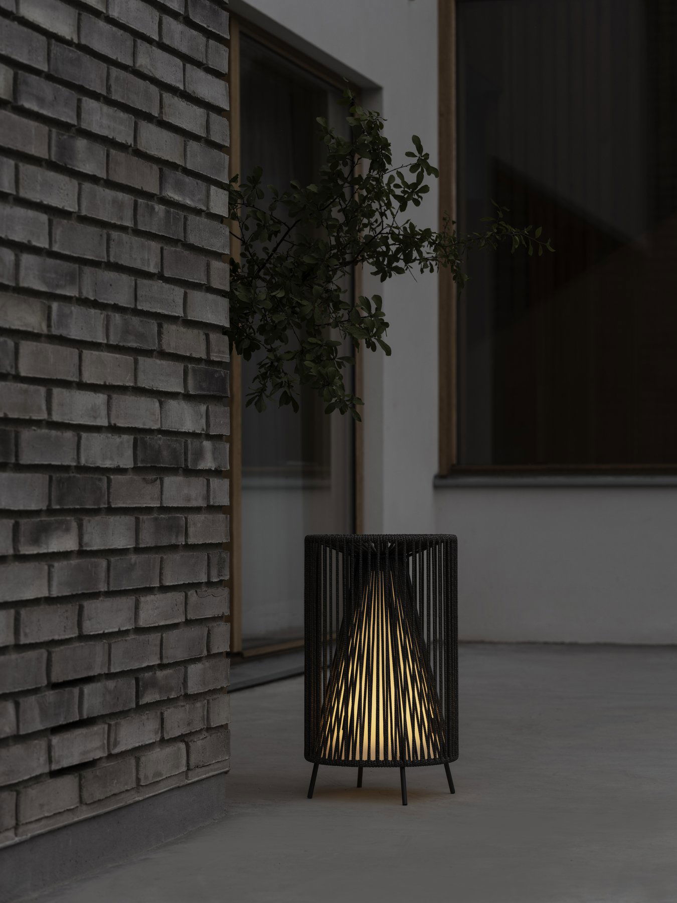 Stilvolle schwarze Lampe, die einen modernen Außenbereich neben einer strukturierten Ziegelwand beleuchtet.