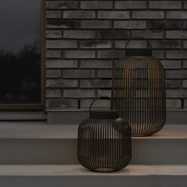 Elegante schwarze Laternen erhellen die Stufen vor einer strukturierten Backsteinmauer.