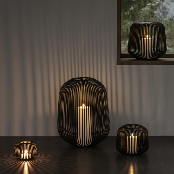 Elegante schwarze Drahtgeflechtlaternen, die sanfte, warme Kerzenlichtschatten in einer gemütlichen Umgebung werfen.