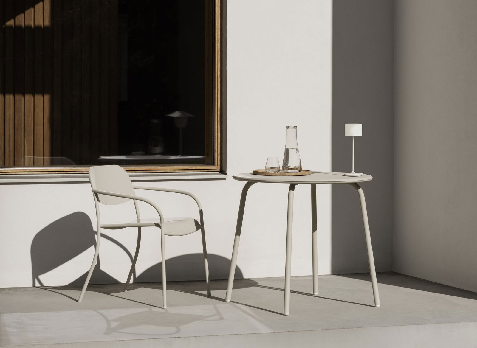 Modern outdoor seating area with a round table, elegant lamp, and minimalist decor.