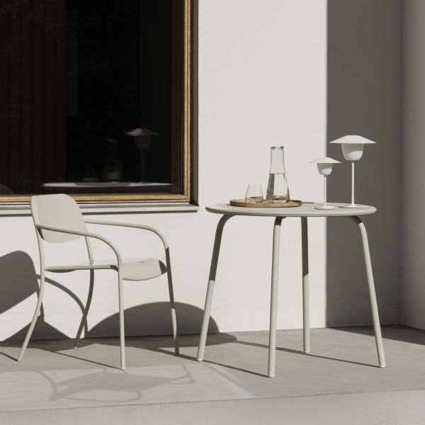 Stylish outdoor setting with a table, chair, and minimalist decor in natural light.