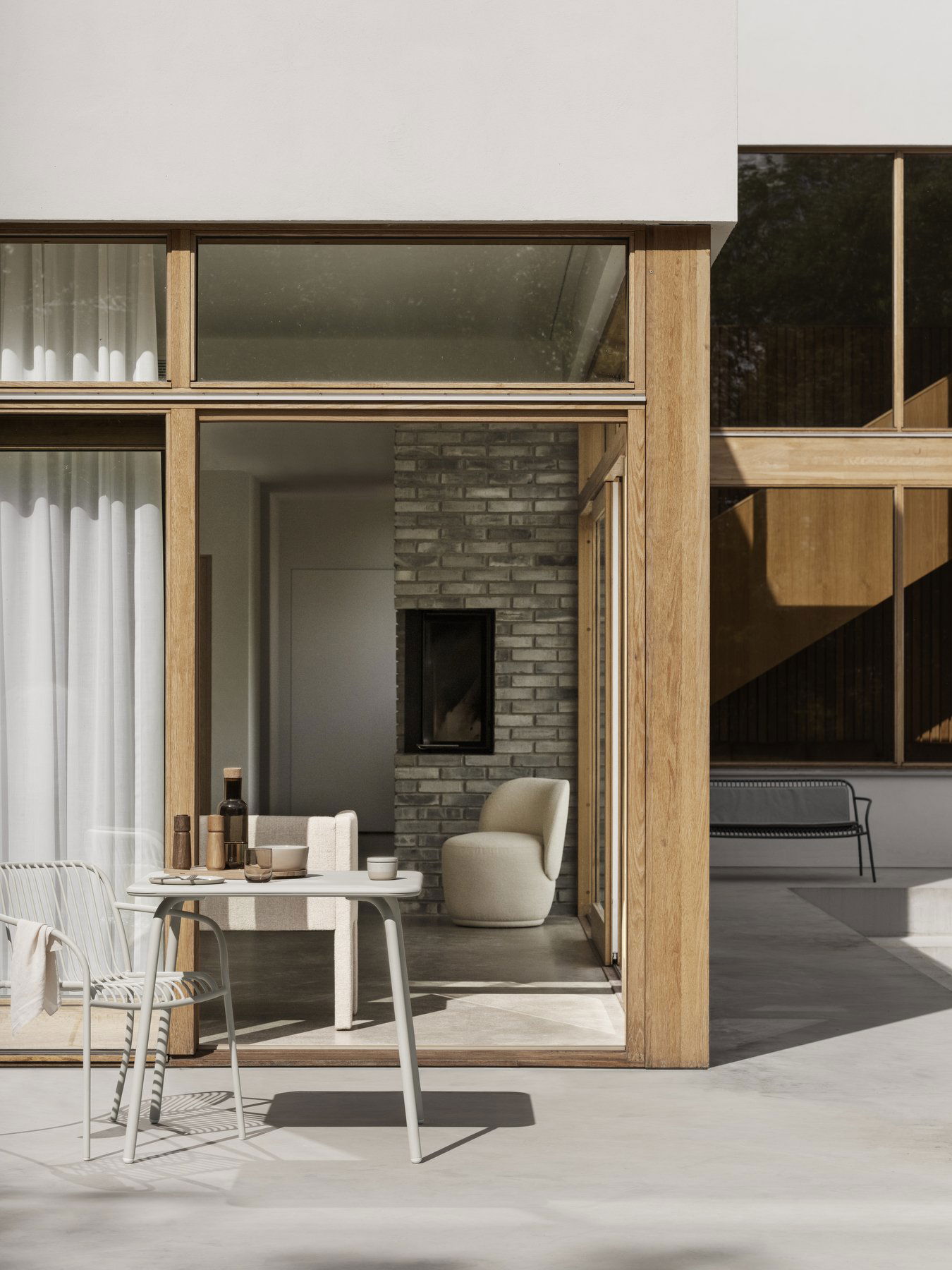 Moderne Außenterrasse mit stilvollen Möbeln und großen Glastüren, die ein gemütliches Interieur präsentieren.