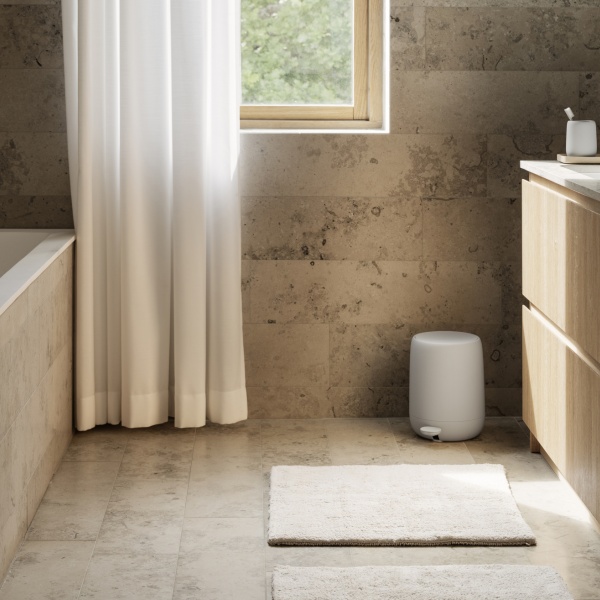 Sleek modern bathroom with natural stone walls, white curtains, and minimalist decor.