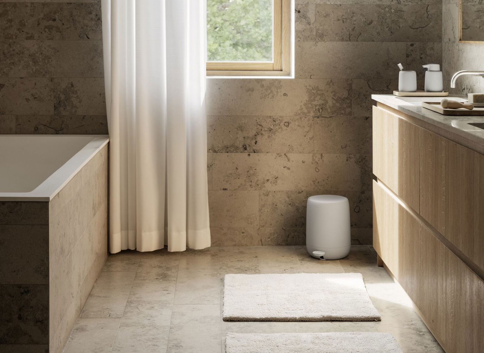 Sleek modern bathroom with natural stone walls, white curtains, and minimalist decor.