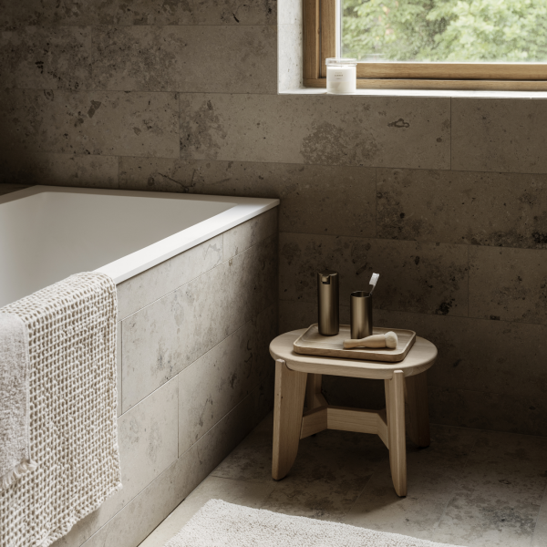 Minimalist bathroom with a soaking tub, natural wood stool, and soft linen towel.
