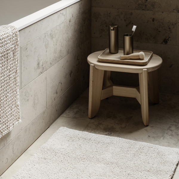 Minimalist bathroom design featuring a wooden stool and elegant decor items.