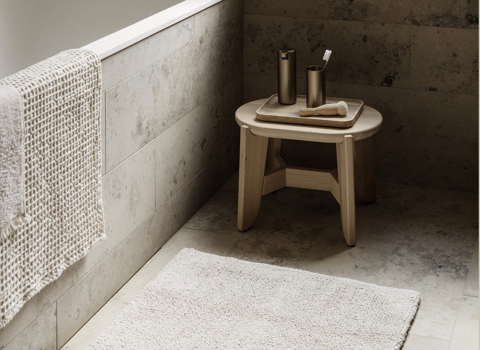 Minimalist bathroom design featuring a wooden stool and elegant decor items.