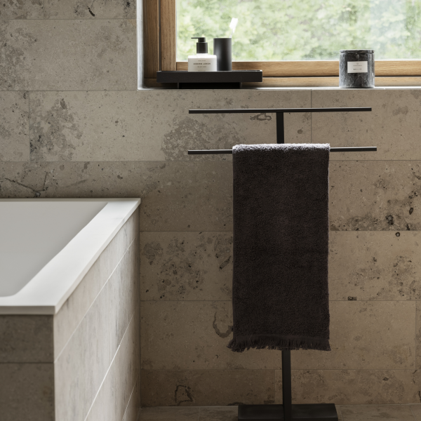 Stylish bathroom with a towel rack, modern decor, and natural light from a window.