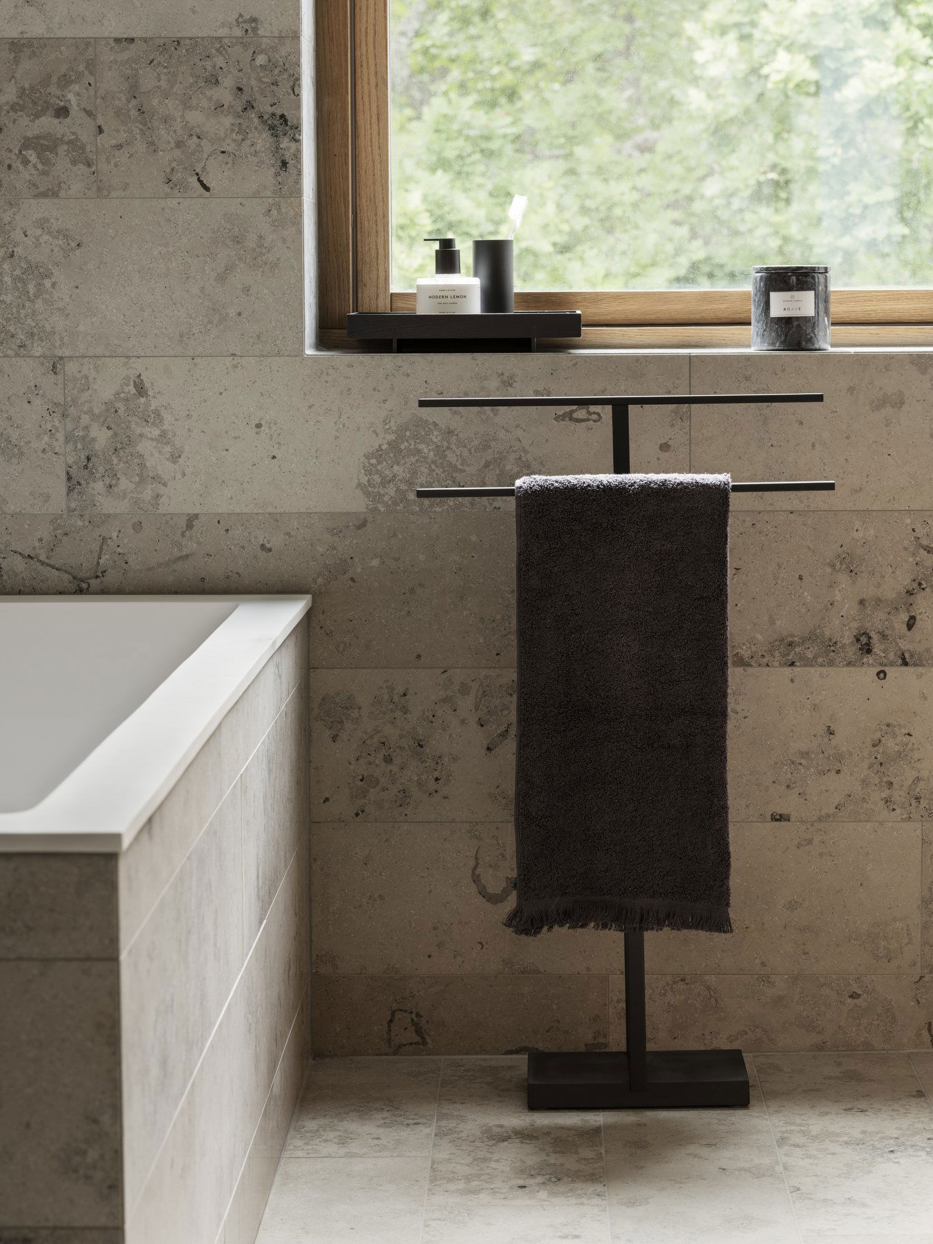 Stylish bathroom with a towel rack, modern decor, and natural light from a window.