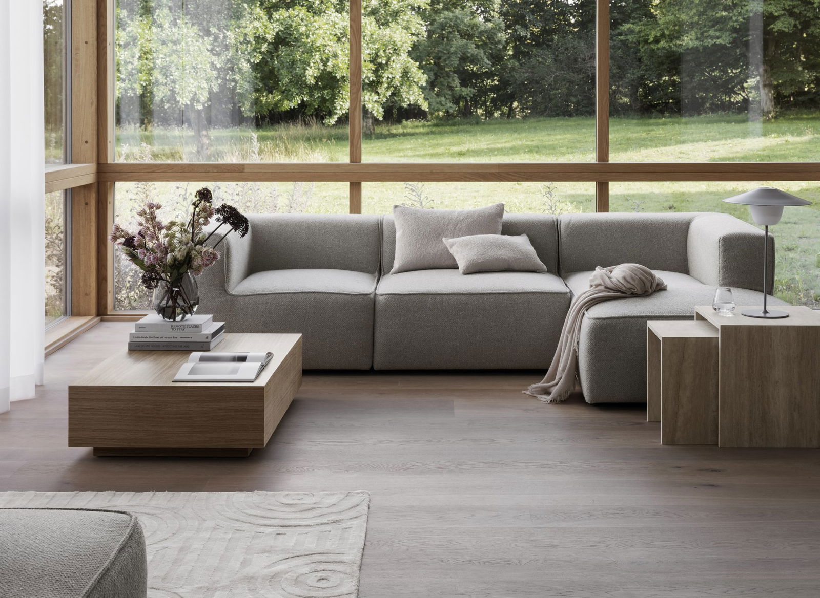 Geräumiges modernes Wohnzimmer mit großen Fenstern, neutraler Möbeln und natürlichem Licht.