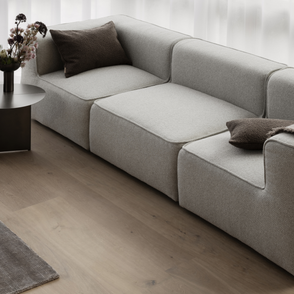 Moderner grauer Ecksofa mit dekorativen Kissen in einem hellen Wohnzimmer.