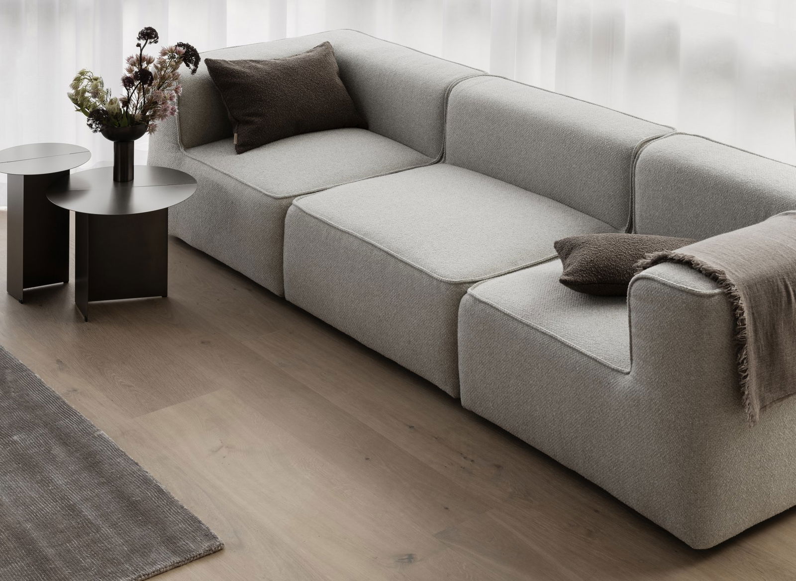 Moderner grauer Ecksofa mit dekorativen Kissen in einem hellen Wohnzimmer.