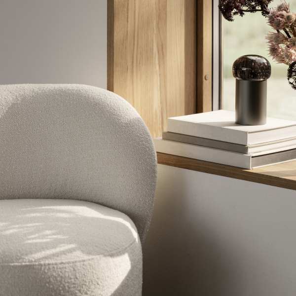 Stilvolles Wohnzimmer-Eck mit einem gemütlichen Stuhl und dekorativen Gegenständen auf einem Holzregal.