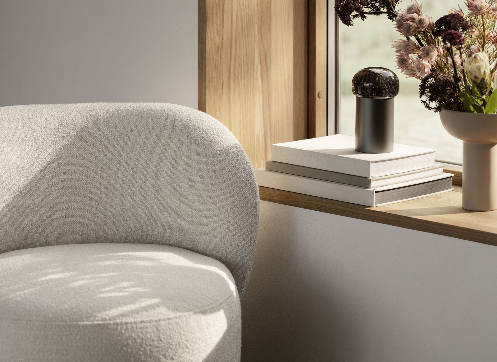 Stilvolles Wohnzimmer-Eck mit einem gemütlichen Stuhl und dekorativen Gegenständen auf einem Holzregal.