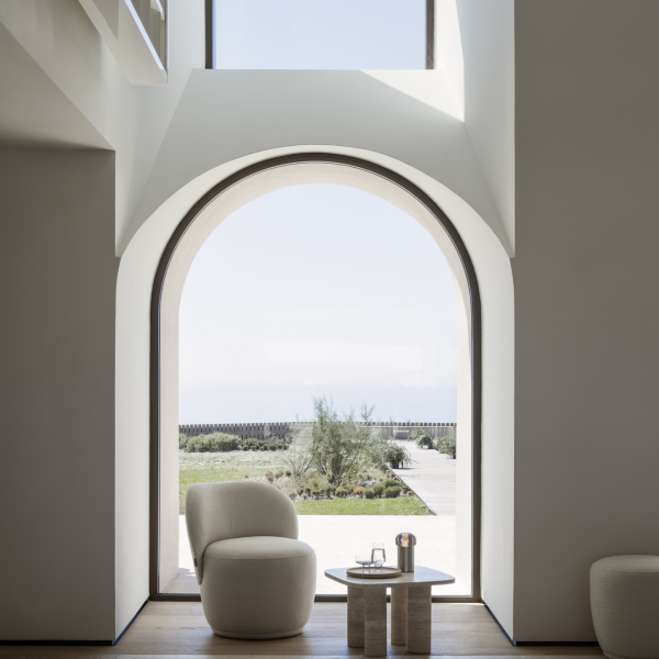 Modernes Interieur mit einem atemberaubenden Bogenfenster, das auf eine ruhige Landschaft im Freien blickt.