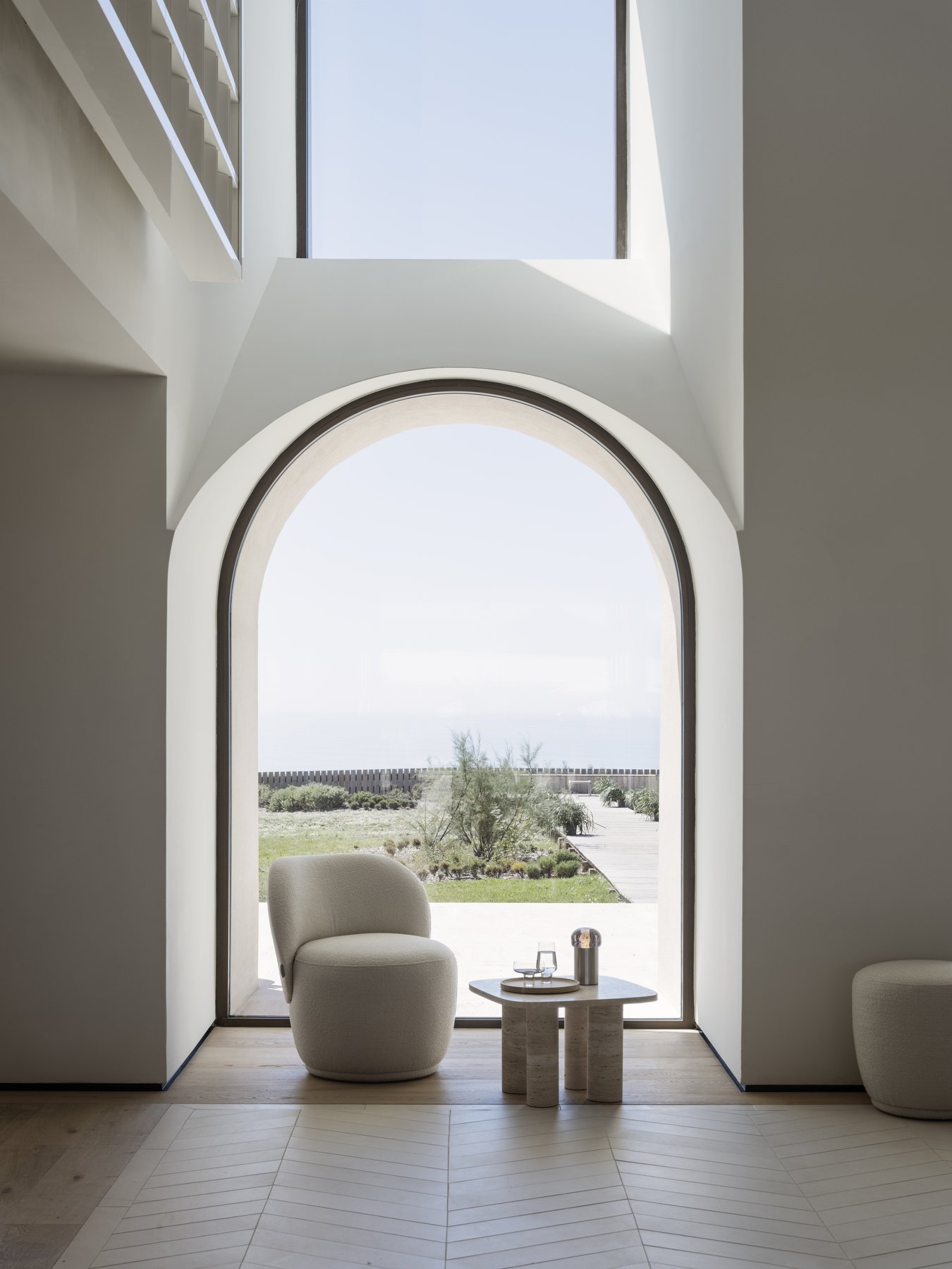 Modernes Interieur mit einem atemberaubenden Bogenfenster, das auf eine ruhige Landschaft im Freien blickt.