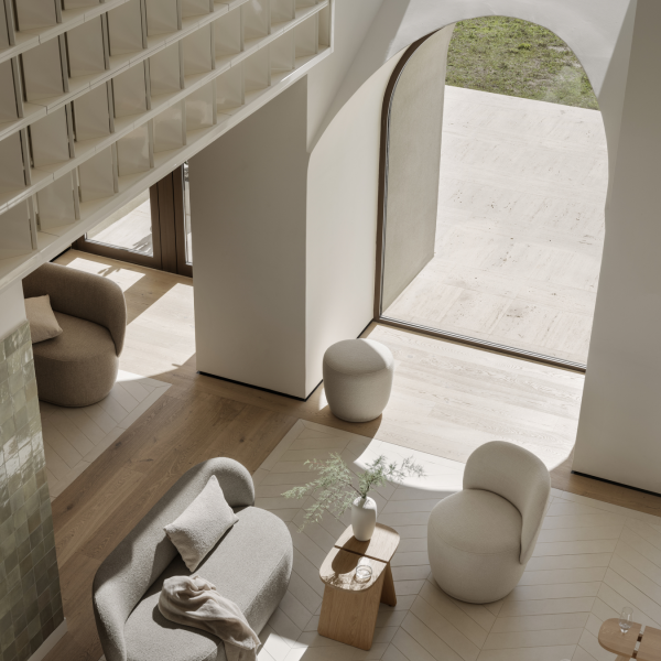 Modern living room with cozy furniture and large arched windows letting in natural light.