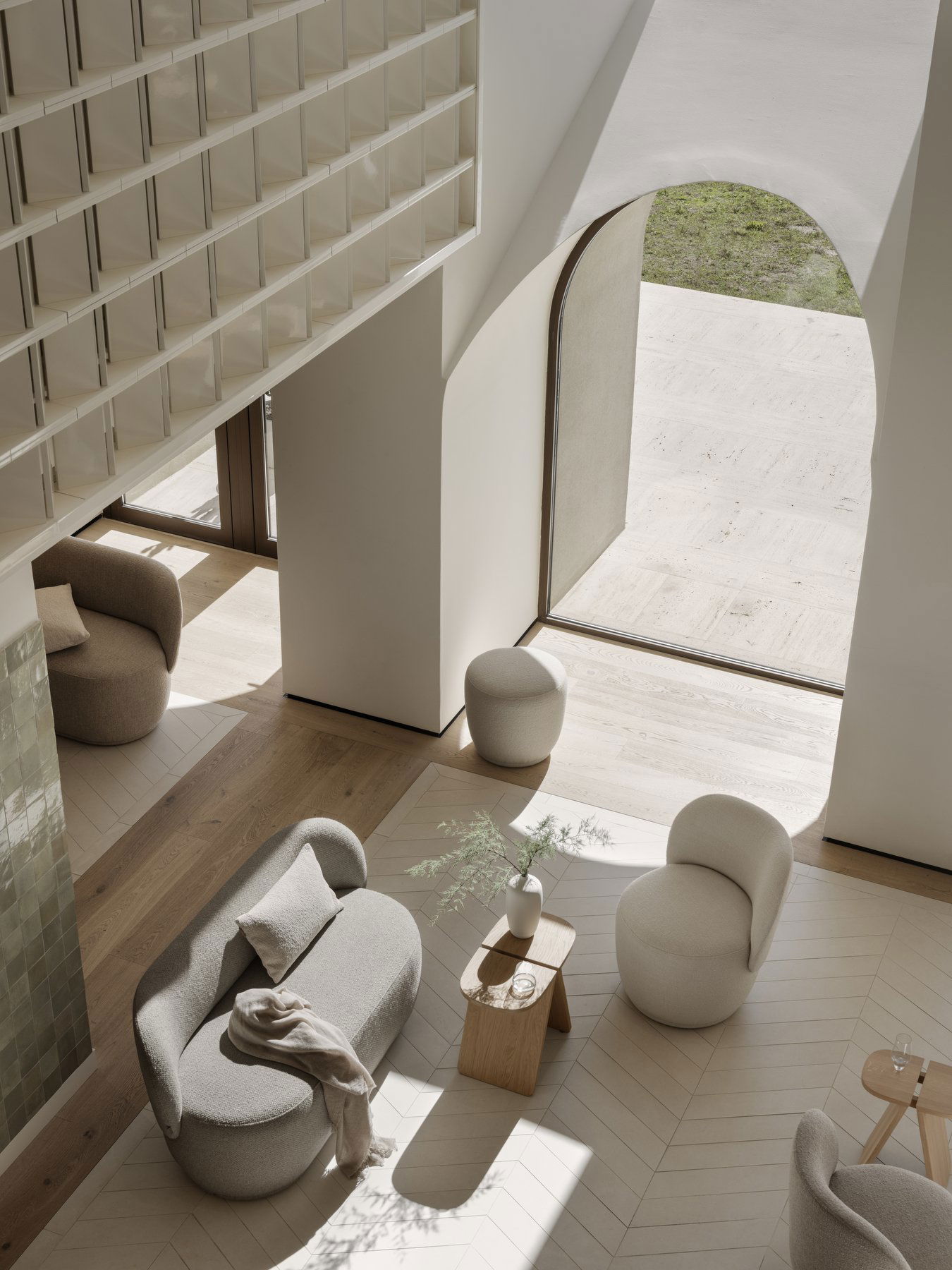 Modern living room with cozy furniture and large arched windows letting in natural light.
