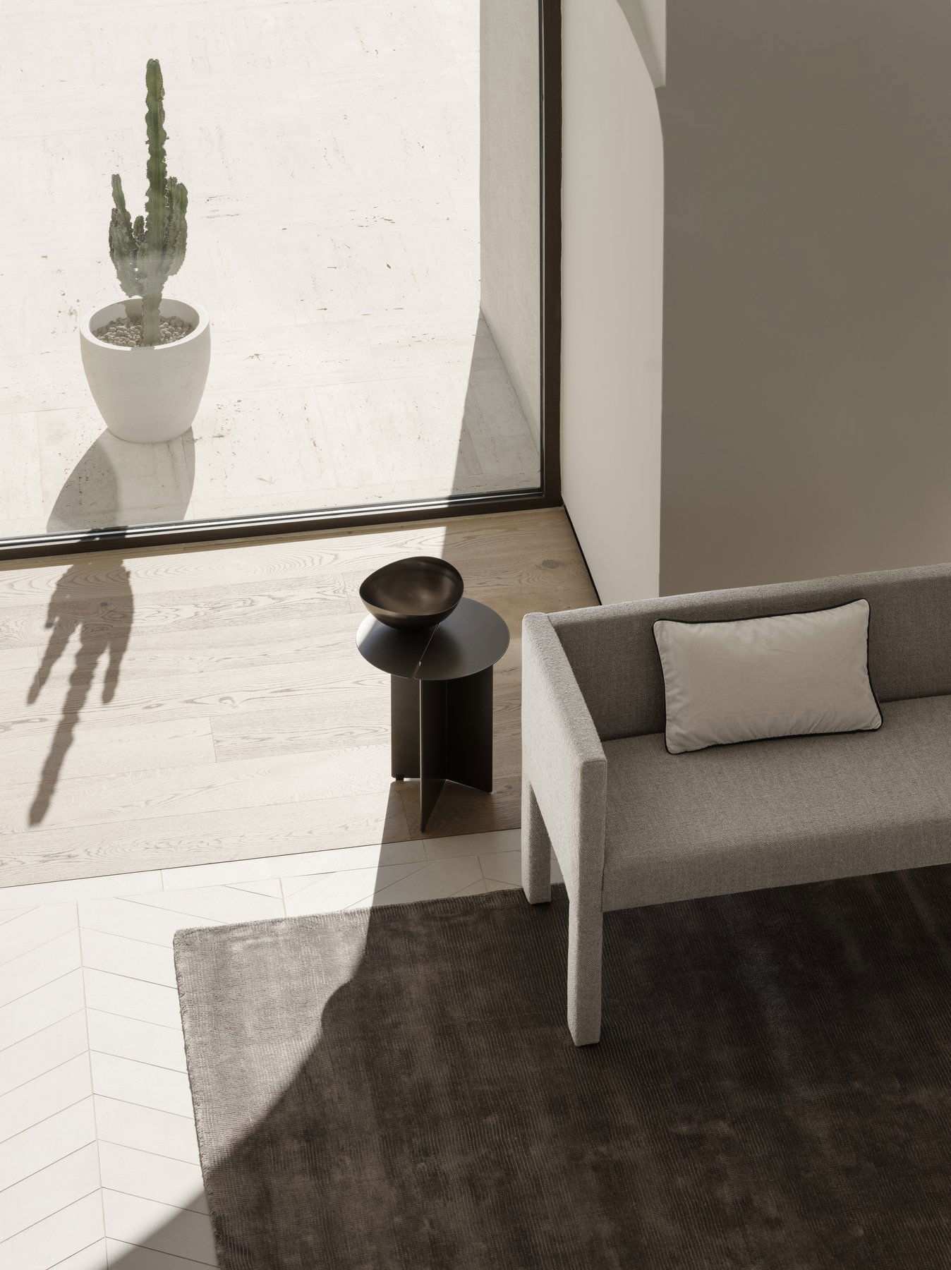 Moderne Wohnzimmerinterieur mit einem stilvollen Sofa, einem dekorativen Hocker und einer Topfpflanze.