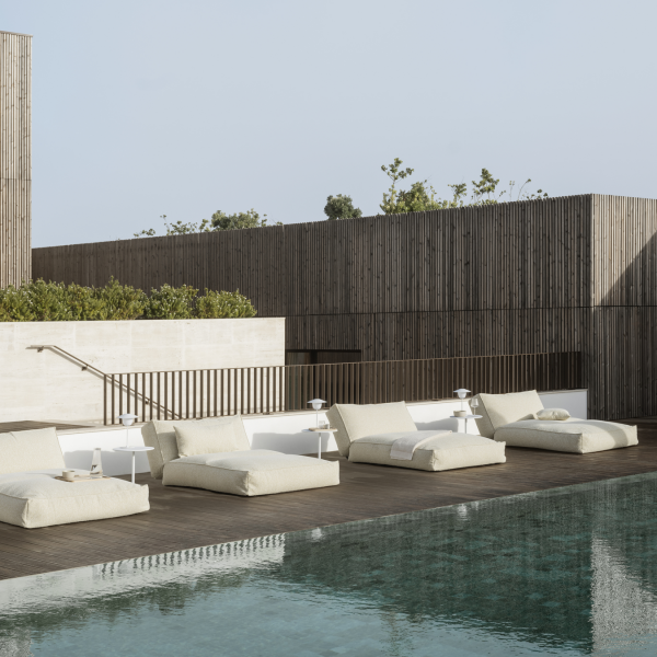 Stylish outdoor lounge area with modern sunbeds by a serene swimming pool.