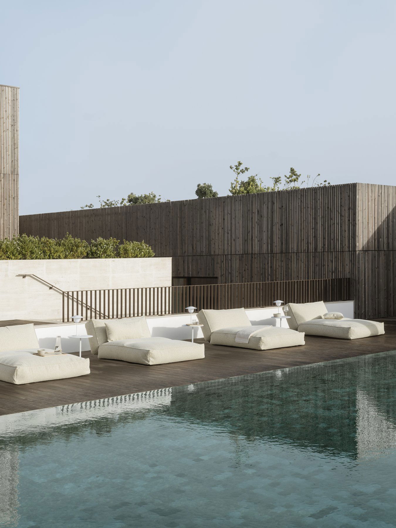 Stylish outdoor lounge area with modern sunbeds by a serene swimming pool.