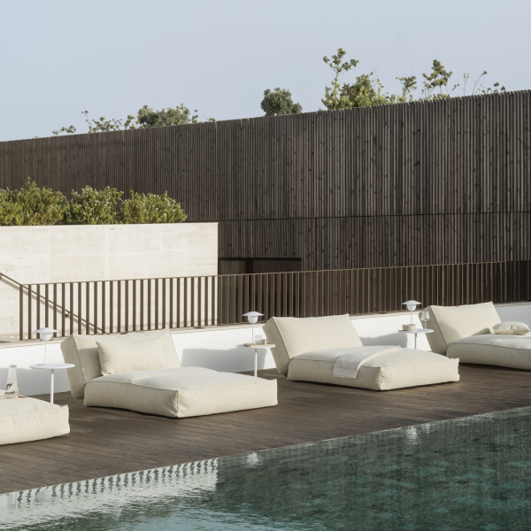 Stylish outdoor lounging area with modern chaise lounges by a serene pool.
