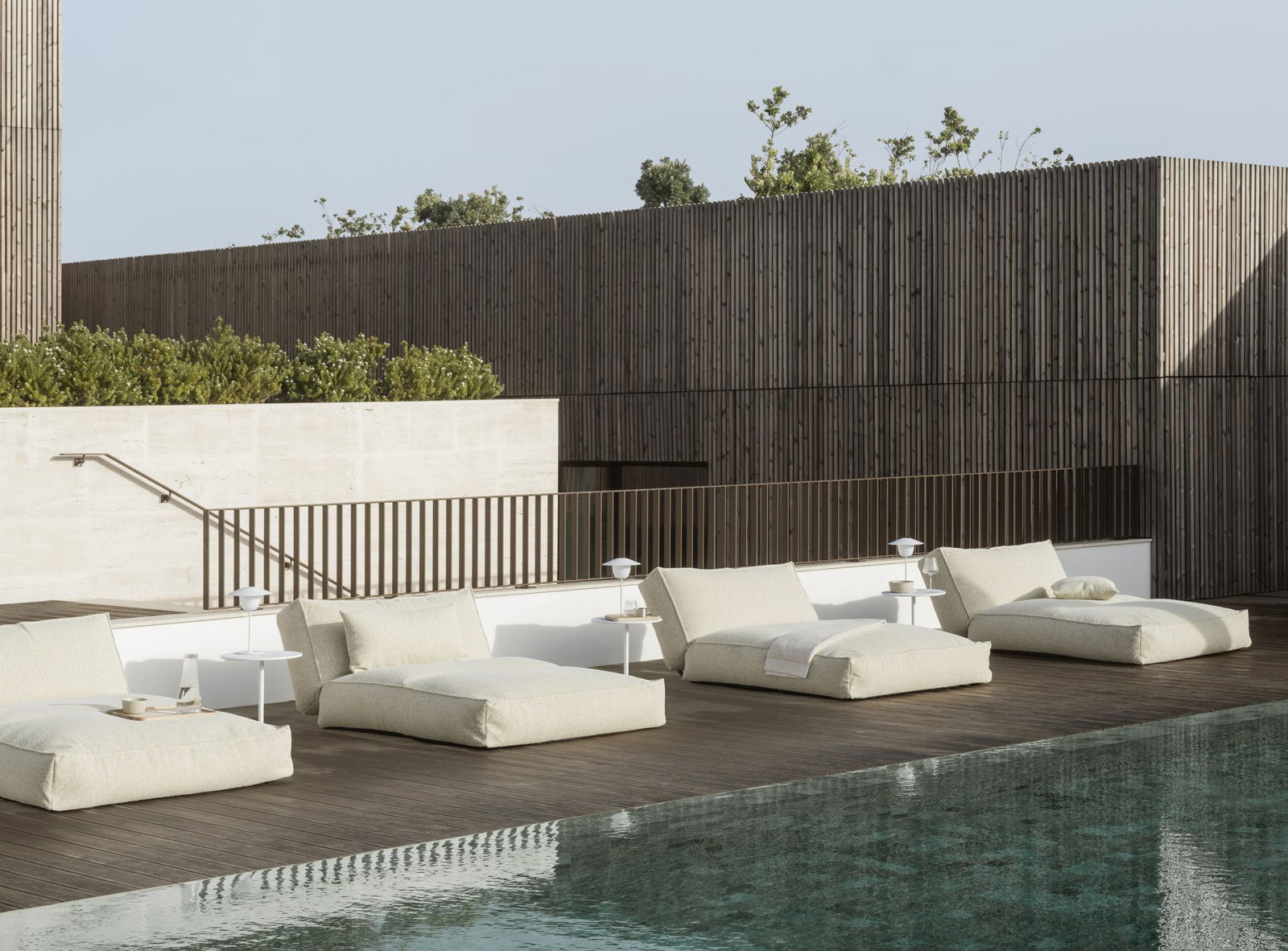 Stylish outdoor lounging area with modern chaise lounges by a serene pool.