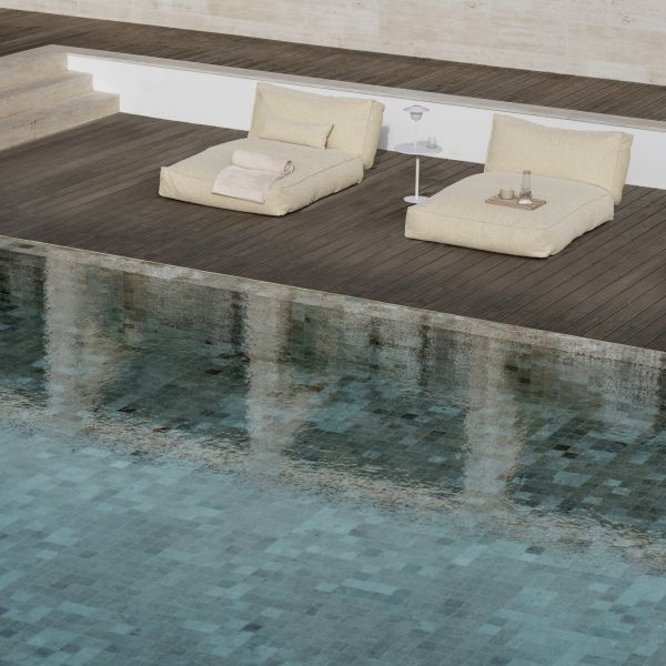 Luxurious poolside loungers beside a tranquil water surface for relaxation.