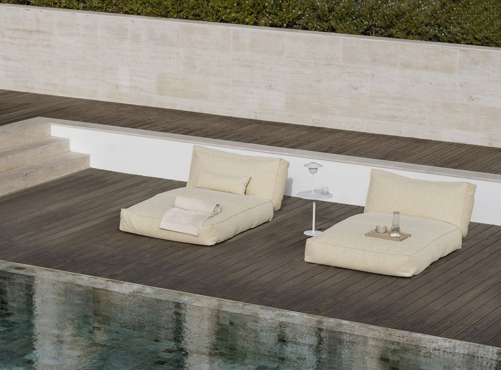 Cozy outdoor lounge area by the pool with cushions and a side table.