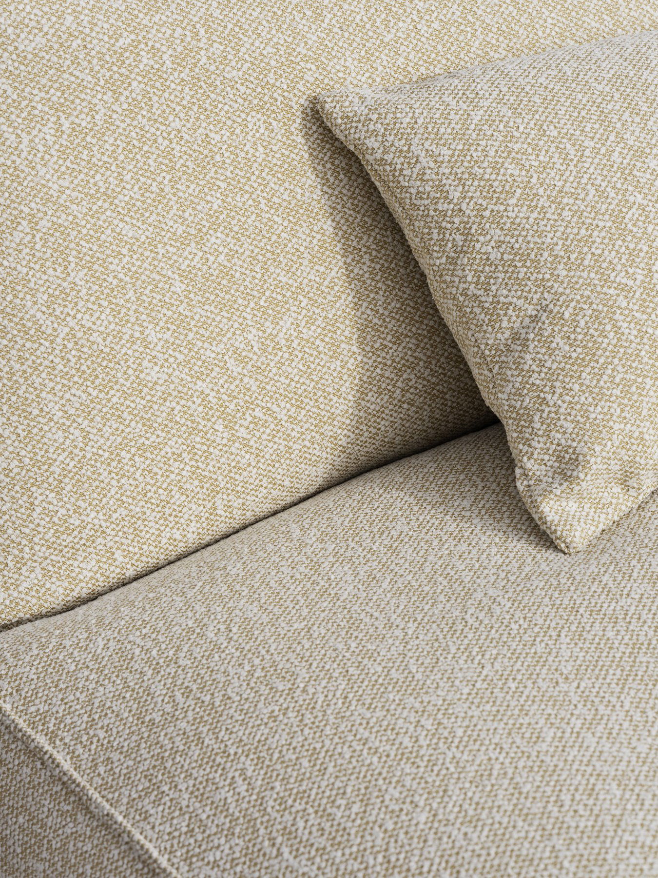Textured beige and white fabric sofa with a decorative pillow.