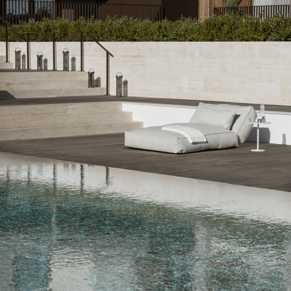 Lounge chair by a serene poolside with modern steps and lush greenery in the background.