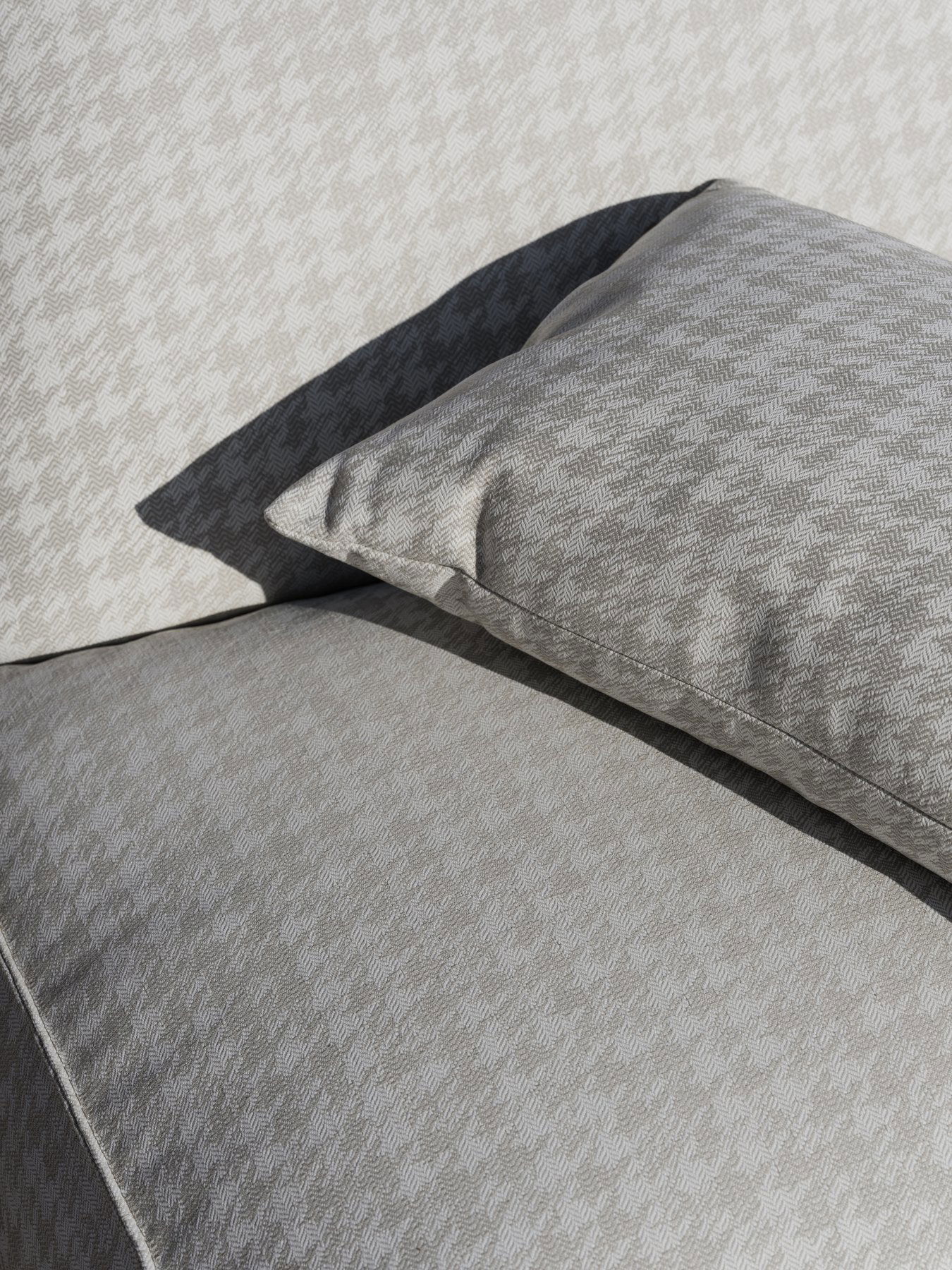Elegant grey houndstooth patterned upholstery featuring a soft matching pillow.