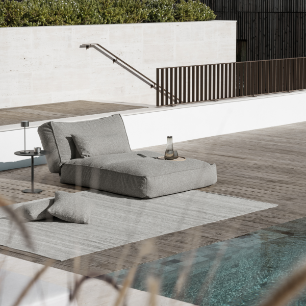 Cozy outdoor lounge chair by a swimming pool on a stylish wooden deck.