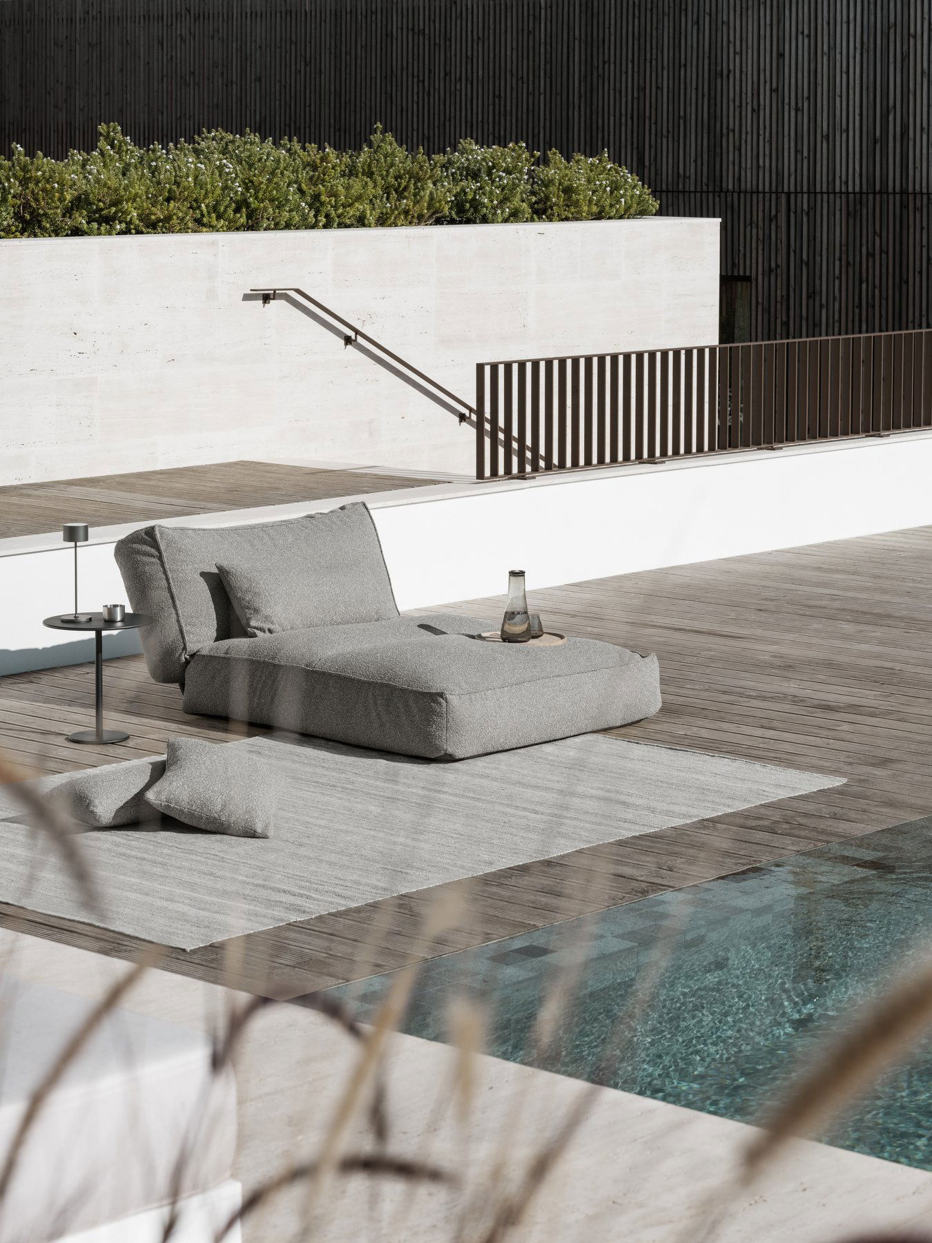 Cozy outdoor lounge chair by a swimming pool on a stylish wooden deck.