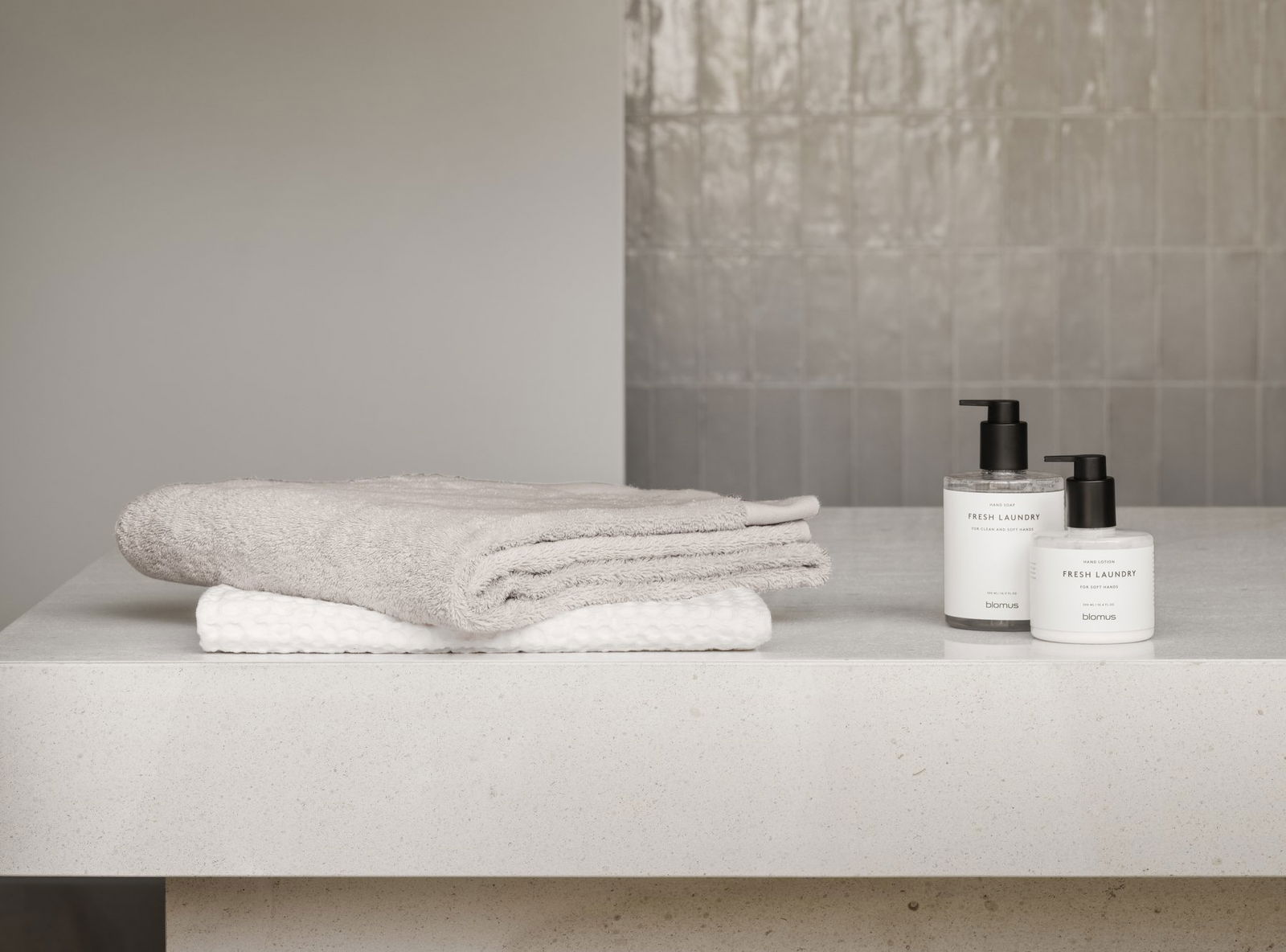 Soft towels and fresh laundry products displayed on a clean bathroom countertop.