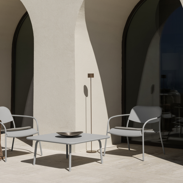 Minimalist outdoor patio with elegant chairs and a stylish table near arched windows.