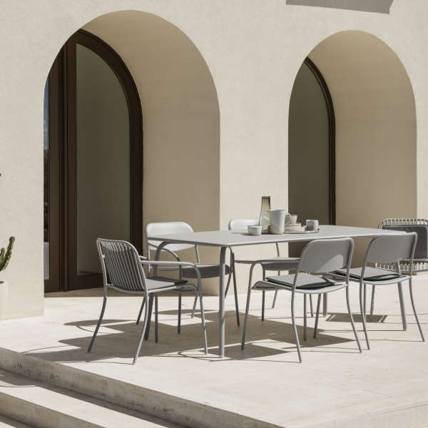 Modern outdoor dining area with a minimalist table and chairs against an elegant backdrop.