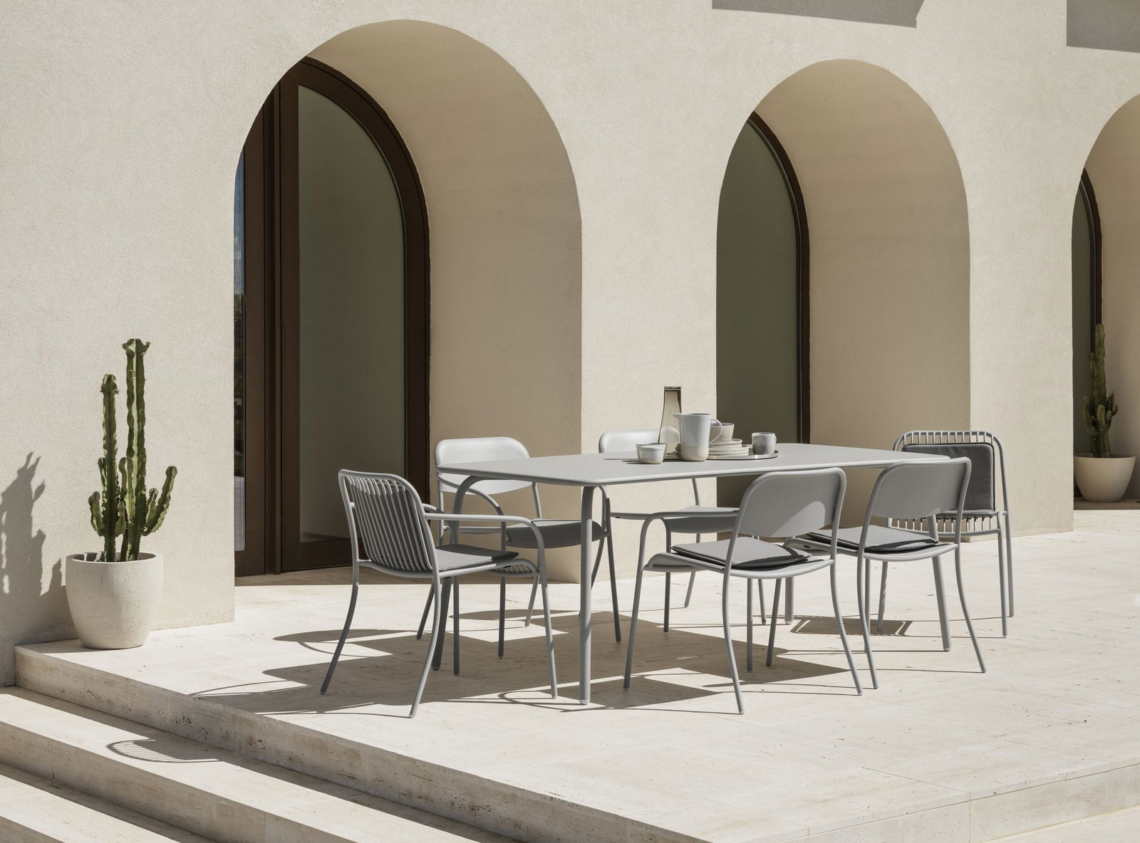 Modern outdoor dining area with a minimalist table and chairs against an elegant backdrop.