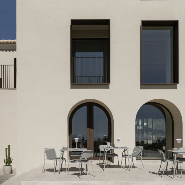 Moderne architektonische Fassade mit großen Fenstern und einem Außenbereich mit Sitzgelegenheiten.