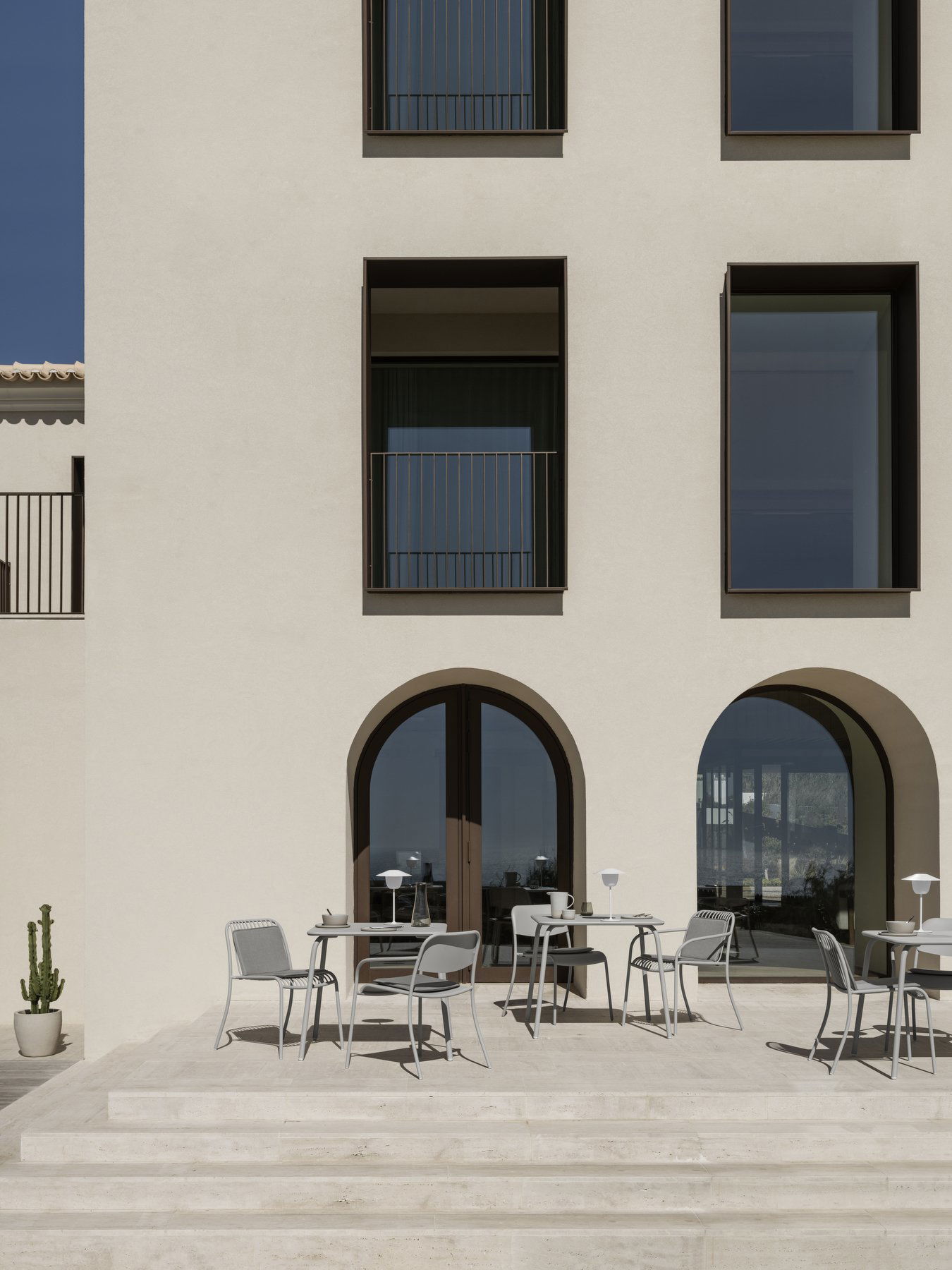 Moderne architektonische Fassade mit großen Fenstern und einem Außenbereich mit Sitzgelegenheiten.
