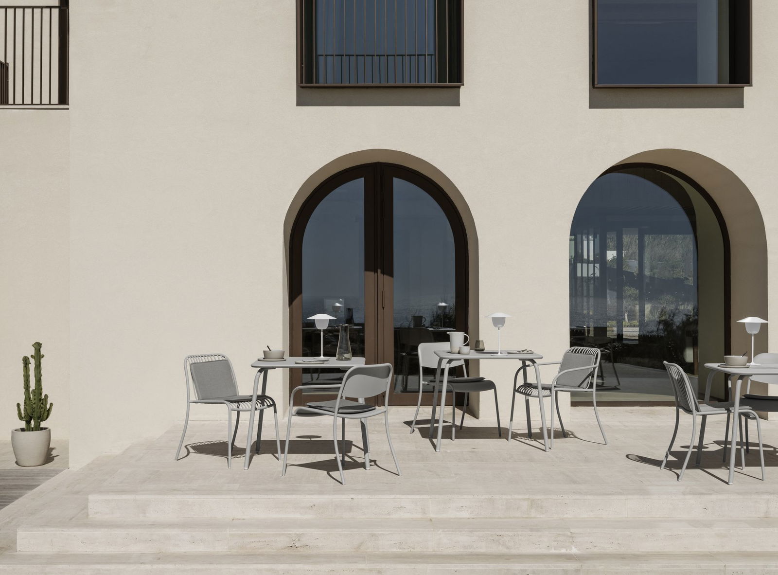 Modern outdoor patio with stylish gray furniture and elegant arches, perfect for dining.