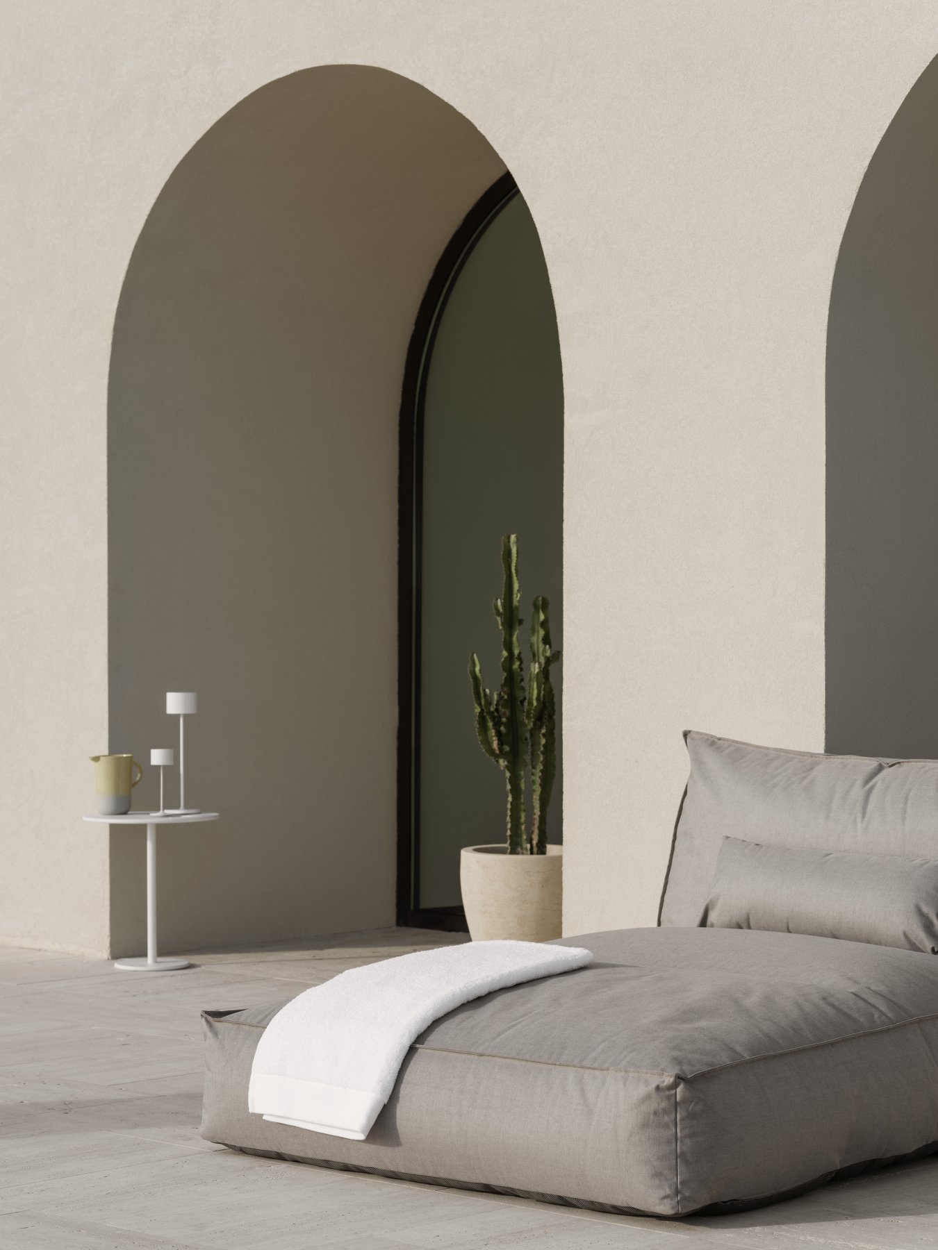 Moderne Außenterrasse mit einem gemütlichen Lounge-Bereich, einem Kaktus und minimalistischer Dekoration.
